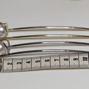 Puede incluir: Dos pinzas para el pelo con detalles de perlas. Las pinzas son de metal y tienen un acabado dorado y plateado. Las pinzas miden aproximadamente 12,5 cm de largo.