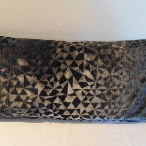 May include: A decorative cushion with a geometric pattern in shades of black, green, and brown.