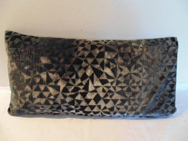 May include: A decorative cushion with a geometric pattern in shades of black, green, and brown.