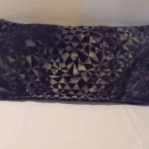 May include: A long, rectangular cushion with a geometric pattern in shades of purple and grey.