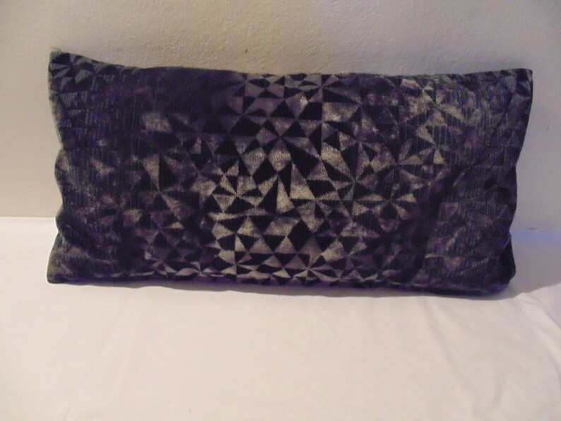 May include: A long, rectangular cushion with a geometric pattern in shades of purple and grey.