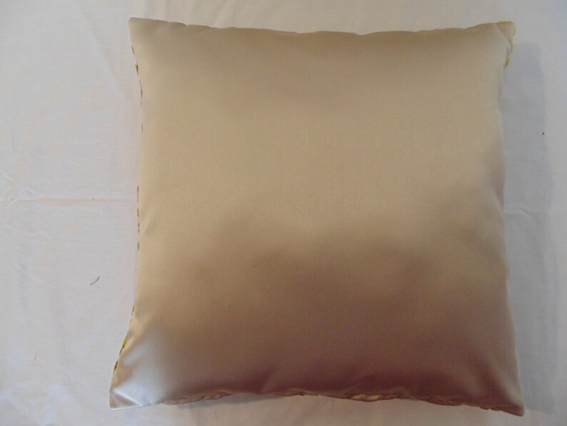 May include: A beige throw pillow with a subtle sheen. The pillow is made of a soft, smooth fabric.