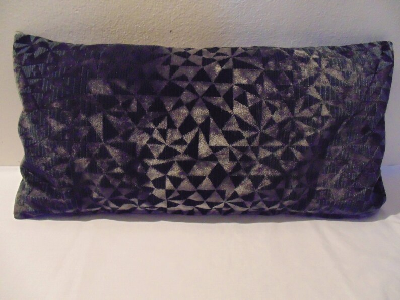 May include: A dark grey and silver geometric patterned throw pillow. The pillow is made of a soft, velvety fabric.