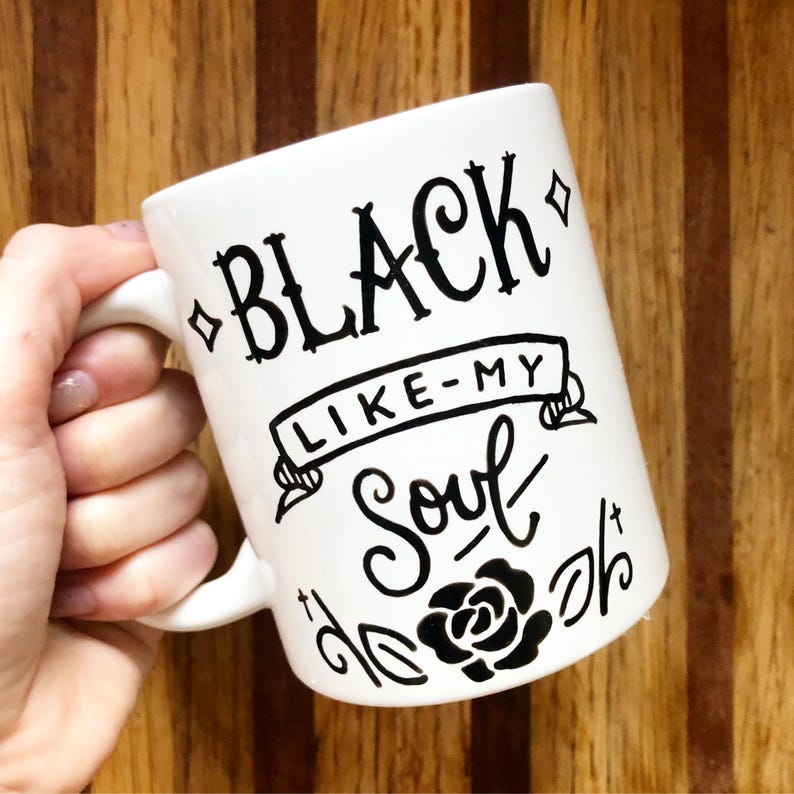 A white mug with black text and graphics on it.