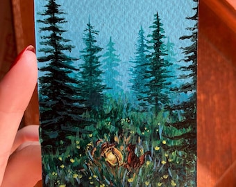 Könnte beinhalten: Miniaturmalerei einer Waldszene mit hohen Nadelbäumen und einem nebligen blauen Himmel. Der Vordergrund zeigt grünes Gras und gelbe Blumen, mit einer leuchtenden Lichtquelle in der Mitte. Das Kunstwerk befindet sich auf einer kleinen rechteckigen Leinwand.