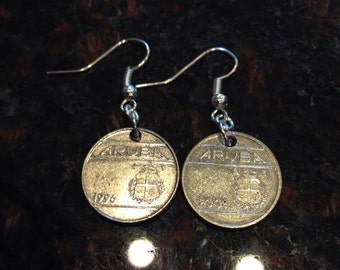 May include: A pair of silver earrings featuring silver coins with the word "ARUBA" and the year "1996" on one coin and "2009" on the other.
