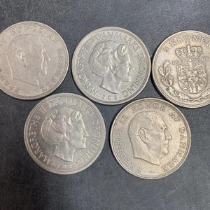 May include: Five silver-colored Danish coins. Two coins feature the profile of Frederik IX with the text 'FREDERIK IX KONGE AF DANMARK'. Two coins show the profile of Margrethe II with 'MARGRETHE II DANMARKS DRONNING'. One coin displays a crown and shield.