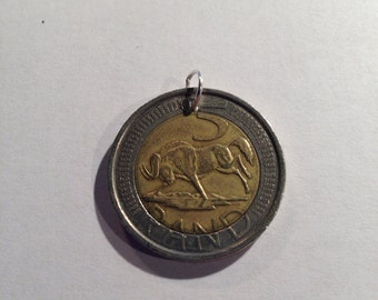 Könnte beinhalten: Eine südafrikanische 5-Rand-Münze aus Silber und Gold mit einem Springbock auf der Vorderseite. Die Münze hat oben ein Loch zum Aufhängen.