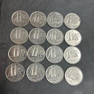Può includere: Una collezione di sedici monete color argento disposte in una griglia quattro per quattro. Ogni moneta circolare presenta un'immagine in rilievo di un veliero sull'acqua, con il numero 25 visualizzato chiaramente a destra dell'imbarcazione.
