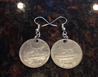 May include: A pair of silver earrings with a coin design. The coins feature a building with the years 2002 and 1996.