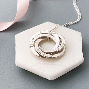May include: Silver necklace with four interlocking rings, each engraved with a name:  "Daisy", "Jack", "Ellie", and "Logan".