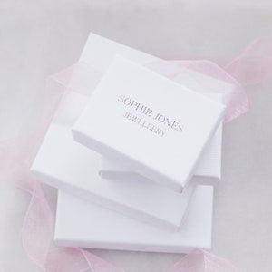 May include: White gift boxes stacked on top of each other. The top box has the text "Sophie Jones Jewellery" printed on it.