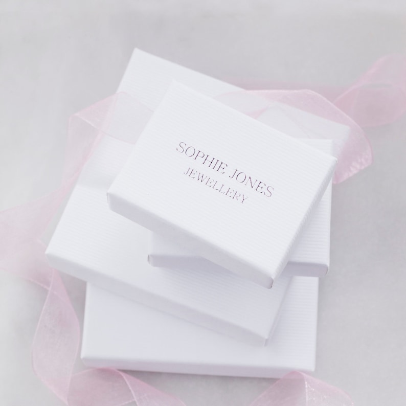 May include: White gift boxes stacked on top of each other. The top box has the text "Sophie Jones Jewellery" printed on it.