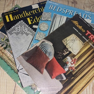 May include: A stack of vintage crochet pattern books with titles like "Handkerchief Edgings", "Bedspreads", and "Modern Trends". The covers feature colorful illustrations and text.