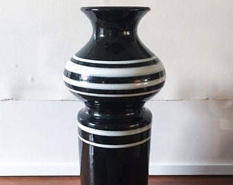 May include: A black and white striped ceramic vase with a wide base and a narrow neck.