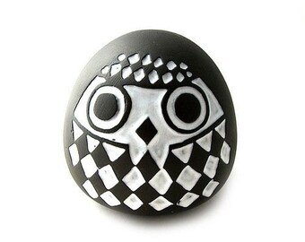 Könnte beinhalten: Schwarze und weiße Keramik-Eulenfigur mit geometrischem Muster. Die Eule hat große, runde Augen und einen Schnabel.
