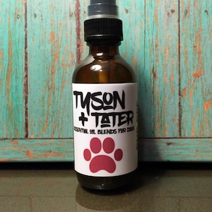 May include: A brown glass bottle with a black spray top and a white label that says "Tyson + Tater Essential Oil Blends for Dogs" with a red paw print.