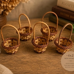 May include: Five small, round, hand-woven wicker baskets with arched handles. Each basket features a light and dark brown woven pattern. A circular graphic overlay on the image displays the text ~4x2” MINI BASKETS HAND WOVEN NATURAL WICKER RUSTIC CHARM.