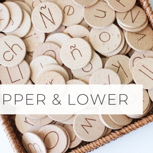 May include: A wicker basket filled with wooden letter tiles, featuring both uppercase and lowercase letters. The tiles are arranged in a random pattern, creating a visually appealing display. The text "UPPER & LOWER" is printed on a white banner below the basket.