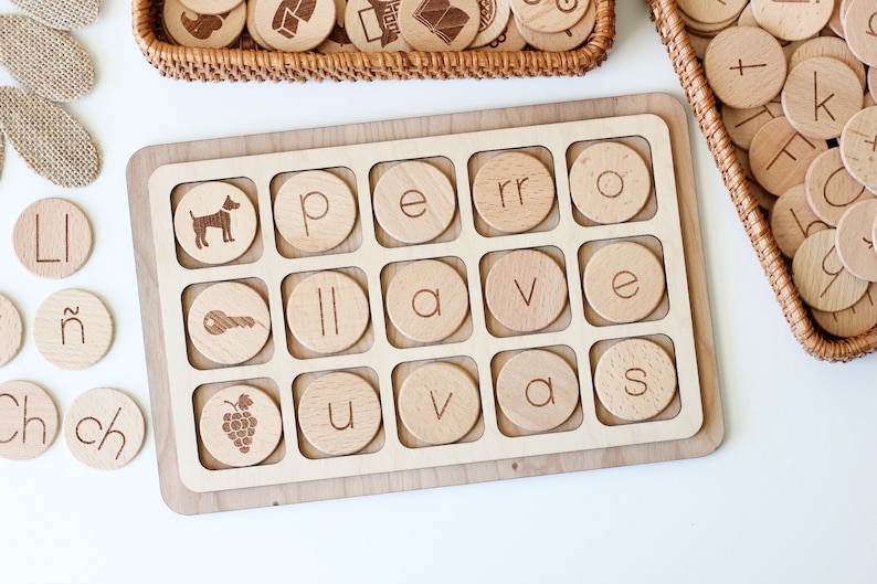 May include: Wooden tray with 18 round wooden tiles, each with a letter or image. The tiles are arranged in a grid pattern. The letters spell out the words "I have a pet".