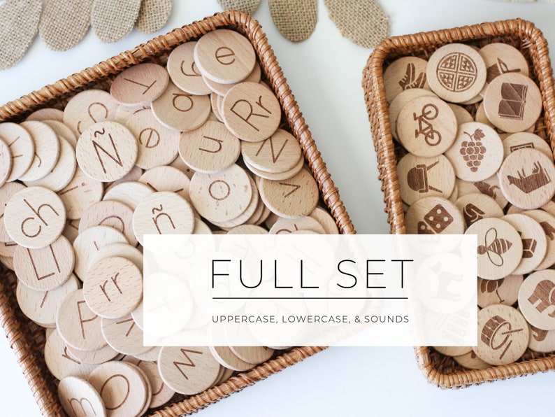 May include: Two wicker baskets filled with wooden alphabet and picture tiles. The baskets are on a white surface. The text "FULL SET UPPERCASE, LOWERCASE, & SOUNDS" is displayed on a white rectangle in front of the baskets.