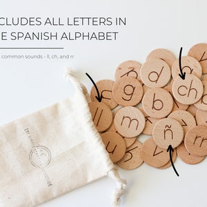 May include: A set of wooden letter tiles in a white drawstring bag. The tiles feature the letters of the Spanish alphabet, including the letters 'ch', 'll', and 'rr'.