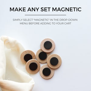 May include: A set of six wooden round magnets with black centers. The magnets are scattered on a white surface next to a white cloth bag. The text "MAKE ANY SET MAGNETIC" and "SIMPLY SELECT "MAGNETIC" IN THE DROP-DOWN MENU BEFORE ADDING TO YOUR CART" is displayed above the magnets.