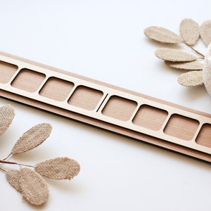 Könnte beinhalten: Holztablett mit zehn quadratischen Fächern, ideal zum Organisieren kleiner Gegenstände. Das Tablett ist aus hellbraunem Holz gefertigt und hat eine natürliche Oberfläche.