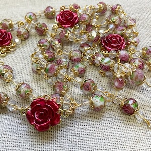 Red rose Catholic rosary featuring dimensional crimson rose beads, delicate pink floral lampwork glass beads, gold-tone links, an Immaculate Mary centerpiece and a Sacred Heart of Jesus medal.