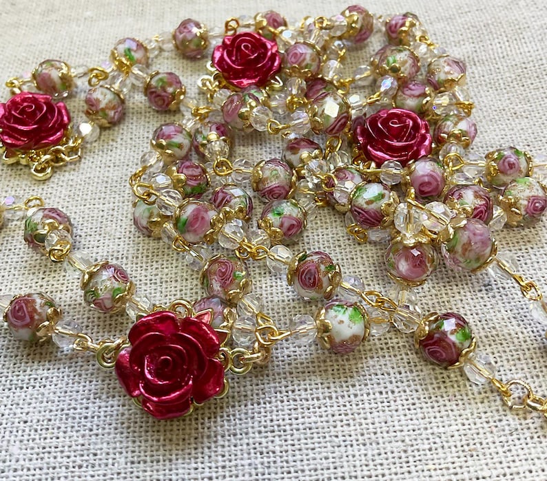 Red rose Catholic rosary featuring dimensional crimson rose beads, delicate pink floral lampwork glass beads, gold-tone links, an Immaculate Mary centerpiece and a Sacred Heart of Jesus medal.