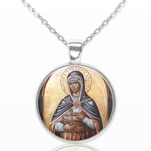 May include: A silver chain necklace with a round pendant featuring a religious icon. The icon depicts a woman in a blue robe holding a cross. The background is a yellow and gold color.
