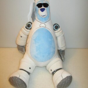 May include: A plush polar bear toy wearing black sunglasses. The bear has a light blue face and belly, with white limbs and torso. It features robotic-style detailing on the arms and legs, including circular joints and grey textured foot pads.