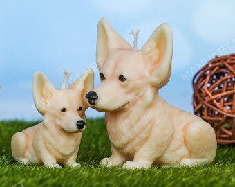 May include: Two cream-colored candle sculptures of corgi dogs. The larger corgi is sitting with its head tilted to the side, while the smaller corgi is sitting with its head facing forward. Both corgis have black eyes and noses.