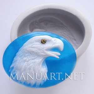 May include: A white eagle head sculpture with a yellow eye, set against a blue background. The sculpture is in a silicone mould.