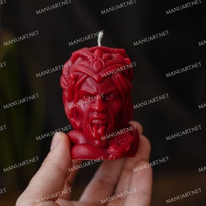 Pu&ograve; includere: Una candela rossa a forma di testa di Medusa, una figura mitologica greca con capelli di serpente. La candela ha un viso dettagliato con un'espressione feroce e una lunga lingua biforcuta.