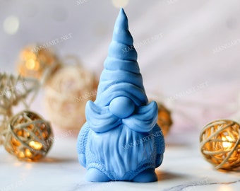 Peut inclure: Une figurine de gnome bleue avec une barbe blanche et un chapeau pointu. Le gnome est debout sur une surface blanche avec quelques boules décoratives autour de lui.