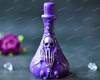 Pode incluir: Uma garrafa decorativa roxa com um design de caveira e mão esquelética. A garrafa tem um pescoço longo e uma base bulbosa. O design é prateado, sobre um fundo escuro.