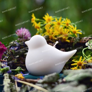 Puede incluir: Vela blanca en forma de pájaro con una mecha sobre un lecho de flores secas y vegetación.