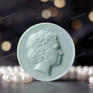 Può includere: Un sapone rotondo blu chiaro con un profilo dettagliato della regina Elisabetta II in rilievo. Il sapone è circondato da una collana di perle bianche.