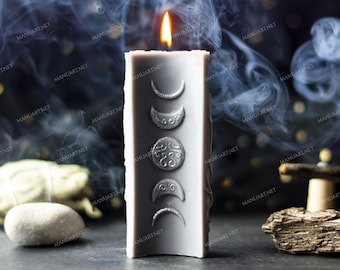 May include: A gray candle with a silver design of three moons and a crescent moon. The candle is lit and smoke is rising from the top. The candle is on a dark surface with a gray stone and a piece of driftwood.