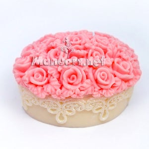 Puede incluir: Un jabón redondo y decorativo con un diseño de rosas rosas en la parte superior y una base color crema. El jabón tiene un borde de encaje alrededor de la base y el texto "Mandarinnet" es visible en la parte superior.