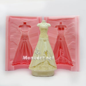 May include: A white silicone mold for making a wedding dress cake topper. The mold is shown with a finished cake topper in the center.