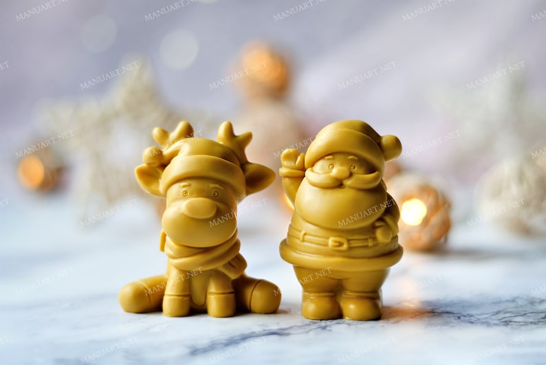 May include: Two small, golden yellow, Christmas-themed figurines. A reindeer with a red and white hat and a Santa Claus with a white beard and a red belt.