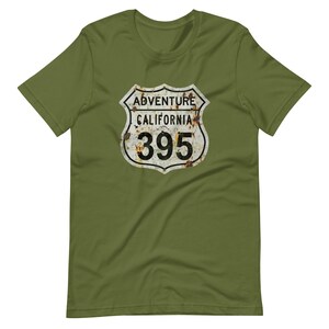 Puede incluir: Una camiseta verde con una señal de carretera de California de estilo vintage con el texto "Adventure California 395".