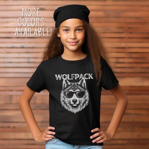 Puede incluir: Camiseta negra con un lobo blanco con gafas de sol y el texto "Wolfpack".