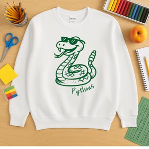 Könnte beinhalten: Weißes Sweatshirt mit einer grünen Cartoon-Schlange, die eine Sonnenbrille trägt. Das Wort "Pythons" steht in Grün unter der Schlange. Ein lässiges, bequemes Oberteil für den Alltag.