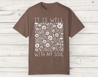 Puede incluir: Una camiseta marrón con un diseño floral blanco y el texto "It is well with my soul".