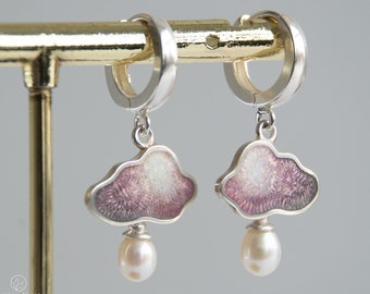 May include: A pair of silver hoop earrings with a pink and white cloud charm and a pearl dangling from each cloud.