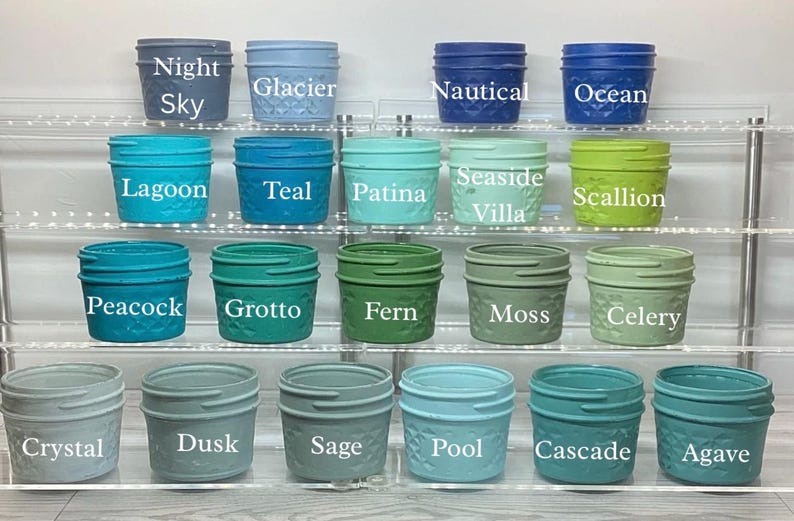 May include: A collection of small, decorative jars in various colors, including Night Sky, Glacier, Lagoon, Teal, Peacock, Grotto, Crystal, Dusk, Sage, Pool, Cascade, and Agave. Each jar has a textured pattern and a matching lid. The names of the colors are printed on the jars.