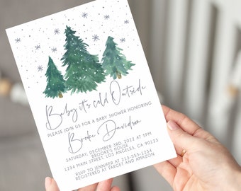 May include: A baby shower invitation with a winter theme. The invitation features watercolor illustrations of evergreen trees and snowflakes. The text reads "Baby it's cold Outside" and includes event details.